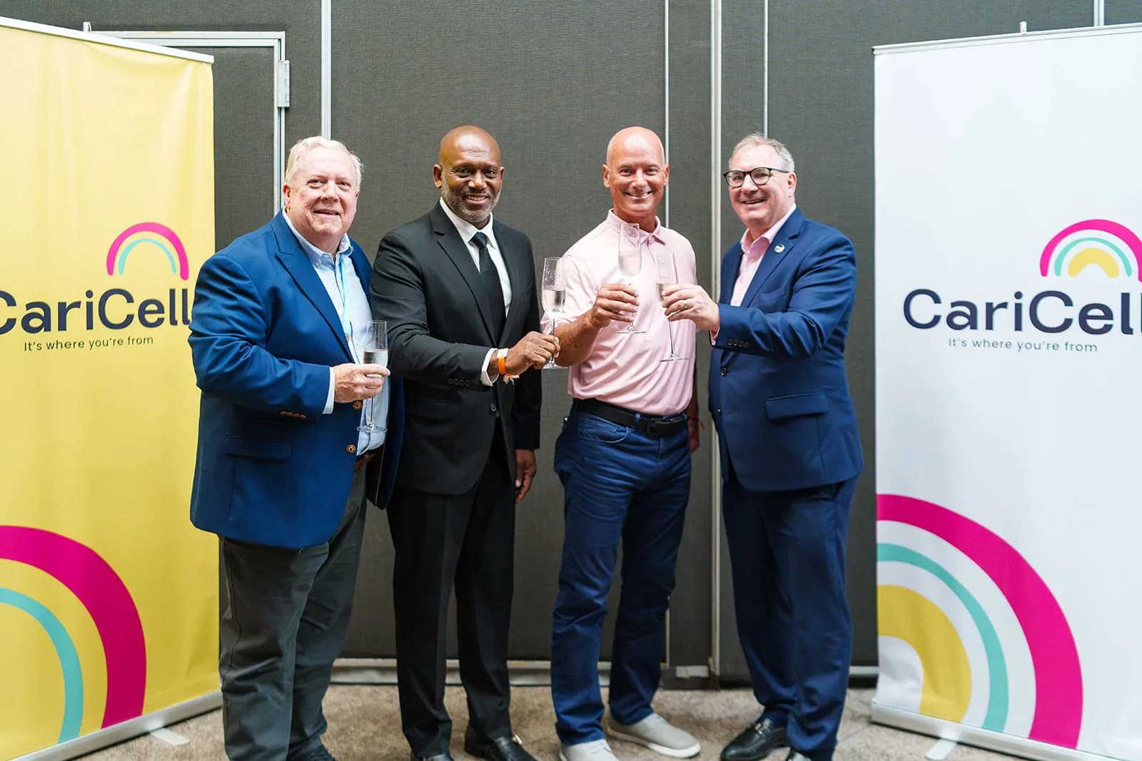 Four people raise a toast in front of CariCell banners at the launch announcement